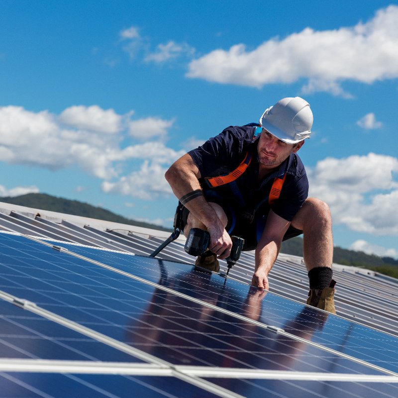 worker installing solar panels on a roof