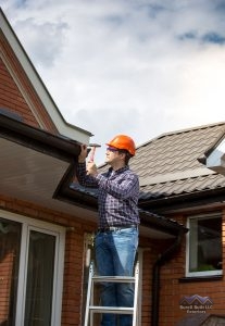 Man on Ladder Inspecting Roof